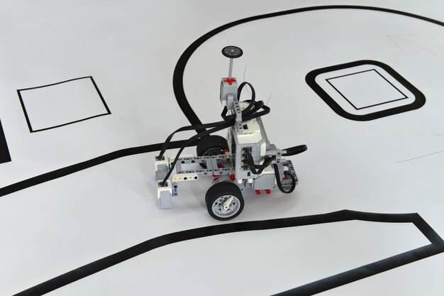 Robot programable con ruedas que se desplazan por una carretera de papel. Coche robótico de juguete con capacidad para evitar obstáculos y seguir la línea.