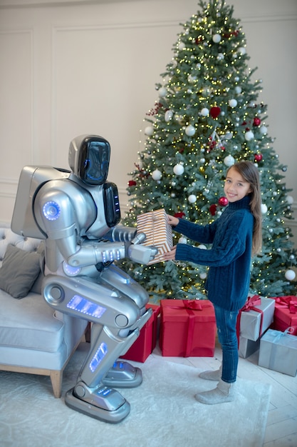 Roboter, der einem lächelnden Mädchen ein Weihnachtsgeschenk gibt