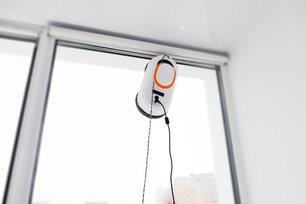 Roboter-Fensterputzer arbeiten an schmutzigen Fenstern und reinigen das Haus mit intelligenten Geräten automatischer Staubsauger ...