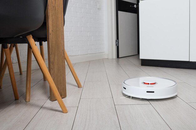 Roboter-Staubsauger entfernt Staub im Zimmer auf dem Boden. Staubsauger in gewöhnlicher Wohnung. modernes drahtloses haushaltsgerät für die reinigung des hauses. Smart-Home-Konzept.