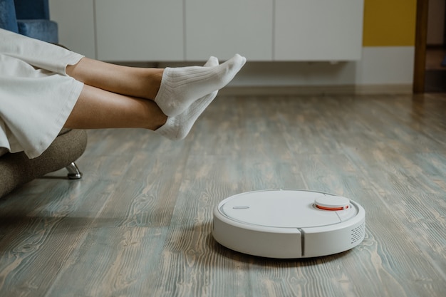 Roboter-Staubsauger Roboter wischt Smart-Home-Roboter-Staubsauger, während sich Frau auf dem Sofa entspannt automatisch