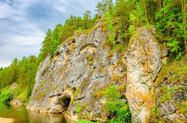 Una roca con una cueva en la orilla del río.