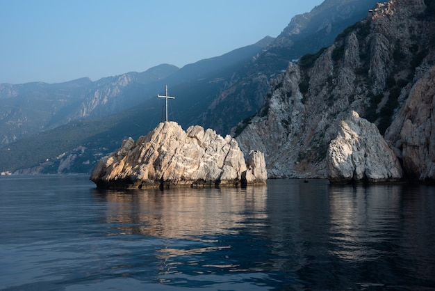 Roca en el mar con una cruz de madera cerca del Monte Athos