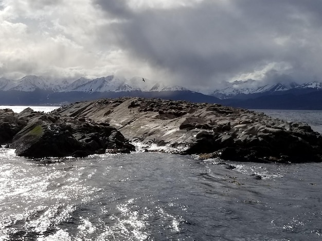 Una roca en el mar con una montaña al fondo