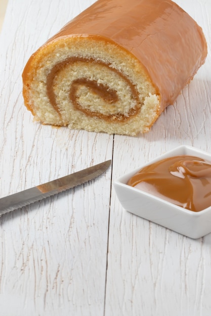 Foto rocambole brasileño de dulce de leche sobre mesa blanca.