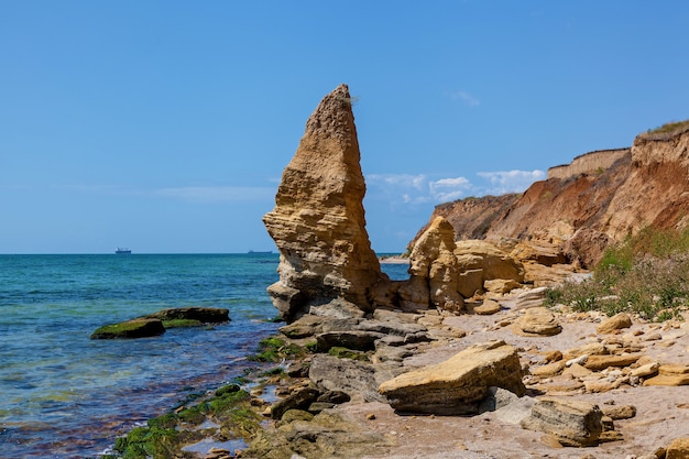 Rocas de arena amarilla y piedras de diversas formas en la costa del Mar Negro. Cielo azul y agua turquesa.