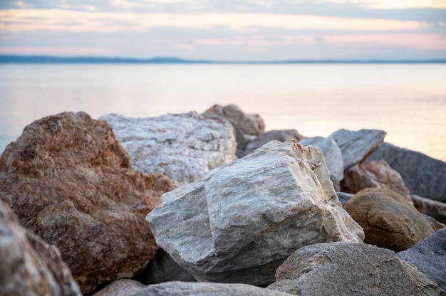 Rocas en la costa del mar Egeo al atardecer, tierra en la distancia en Skala Fourkas, Grecia