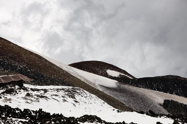 Rocas de lava con nieve en la ladera del volcán Etna, Sicilia, Italia