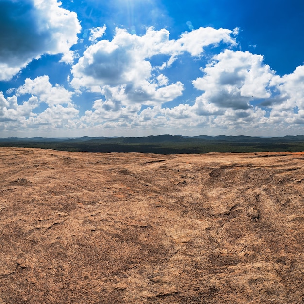 Foto rocas masivas y vista sobre el cielo azul nublado y el bosque verde