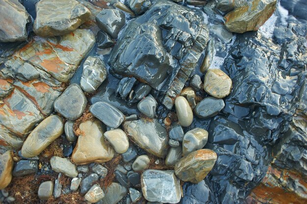 Rocas mojadas en el mar empujadas por una ola Verano