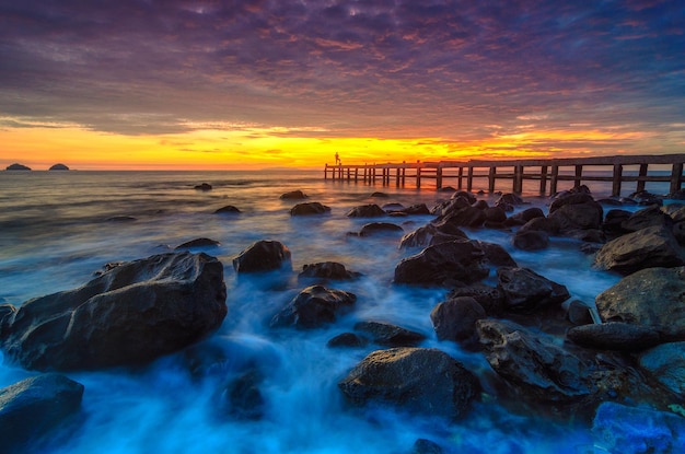 Las rocas en la playa contra el cielo nublado durante la puesta de sol