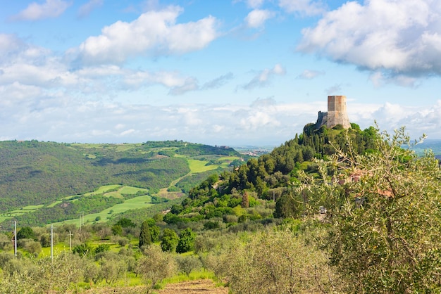 Rocca d'Orcia, ein mittelalterliches Dorf und eine Festung in der Toskana, Italien Einzigartige Aussicht auf den Steinturm, der auf einer Felswand gegen den blauen Himmel mit malerischen Wolken thront