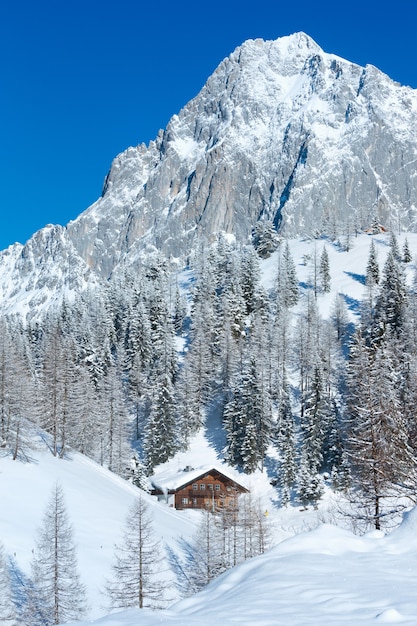 Rocha de inverno com neve fresca caída no topo e casa na ravina.