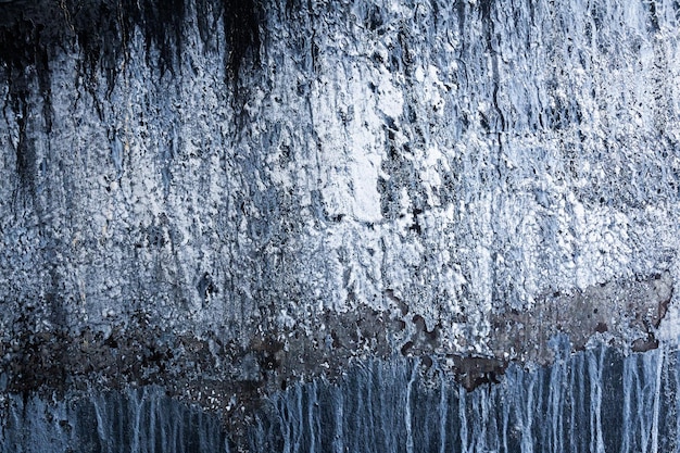 Rocha preta vertical com gelo e neve Abstração de uma rocha gelada com neve
