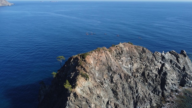 Rocha saindo do mar com canoístas ao fundo