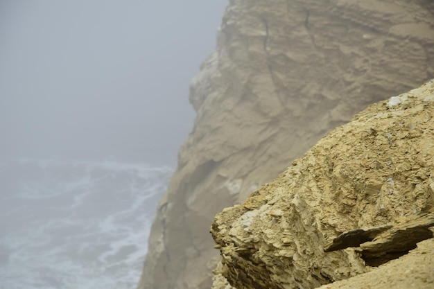 Rochas amarelas no nevoeiro espesso na costa do Parque Nacional de Paracas Peru