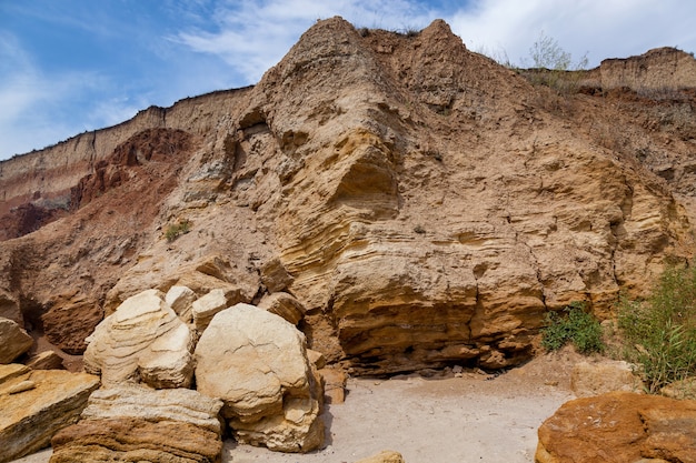 Foto rochas de areia amarela e pedras de várias formas na costa do mar negro. céu azul e água turquesa.