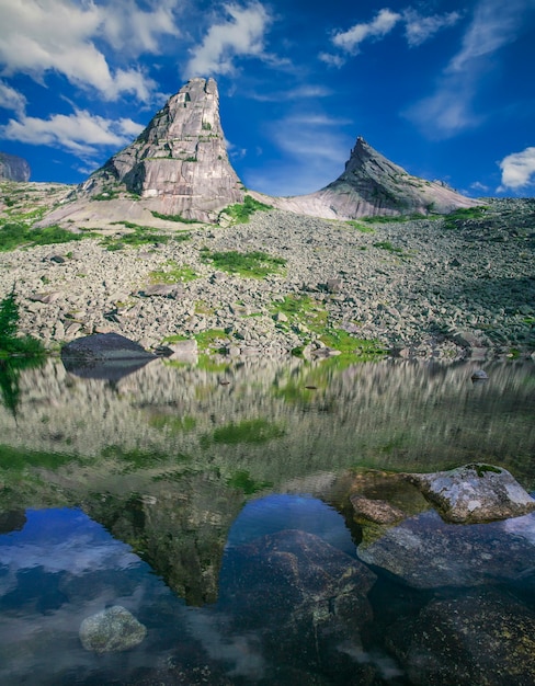 Rochas de formas incríveis são refletidas no lago nas montanhas de Sayan