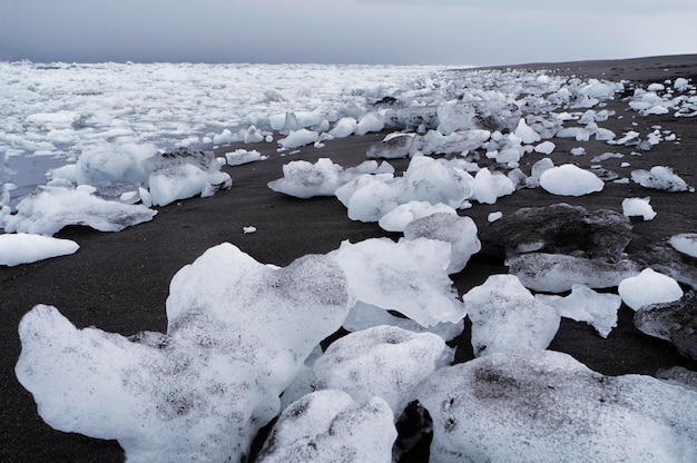Rochas de gelo deitado na praia com areia preta