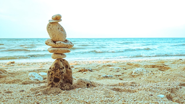 Rochas equilibradas em areia limpa com fundo de praia mostrando o conceito de harmonia