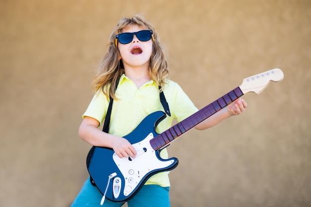 Rock and roll niño pequeño estrella de rock niño pequeño tocando guitarra música al aire libre para niños