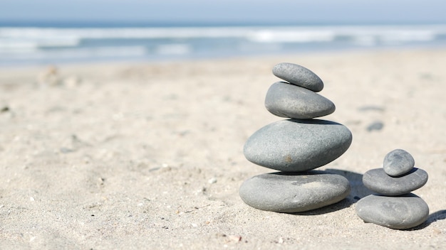 Rock balancieren am Ozeanstrand, Steine stapeln sich durch Meerwasserwellen. Kieselpyramide auf Sand