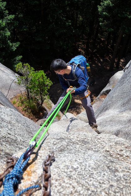 Foto rock climber está descendiendo en rappel por un acantilado durante un día soleado de verano