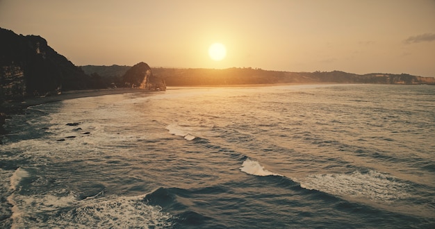 Rock oceano costa pôr do sol com ondas na superfície da água em vista aérea