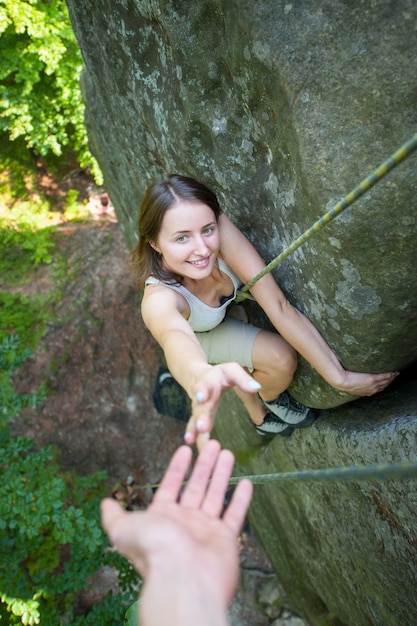 Rockclimber ajudando a alpinista feminina para chegar ao topo da montanha