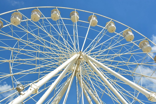 Roda de balsas brancas do parque de diversões no céu azul