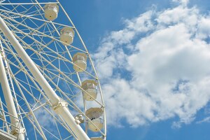 Foto roda de balsas brancas do parque de diversões no céu azul