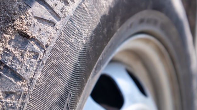 Foto roda de carro suja em uma estrada de solo para o campo. detalhe de close-up de um pneu. transporte, condução e conceito de carro. o carro ficou preso na areia.