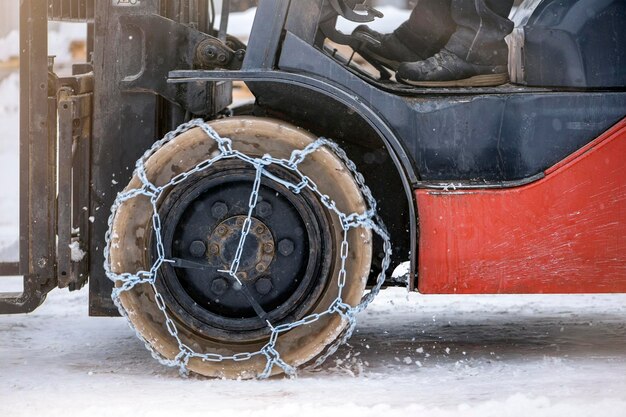 Roda de trator com trator de corrente ou carregador em uma estrada de neve escorregadia, carregadores dirigem na neve com antis