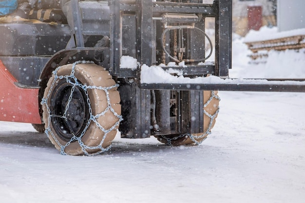 Roda de trator com trator de corrente ou carregador em uma estrada de neve escorregadia, carregadores dirigem na neve com antis