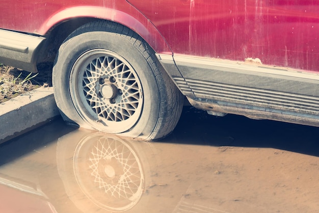 Roda do carro vermelho em uma poça de lama