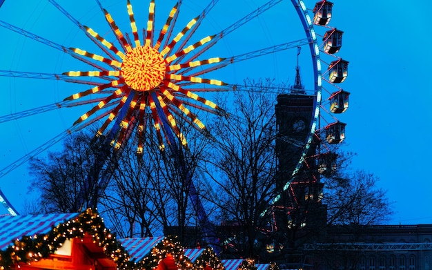 Roda gigante e mercado noturno de Natal na Câmara Municipal de Berlim de inverno, Alemanha. Rua alemã Natal e feira de férias na cidade ou vila europeia. Decoração do Advento e barracas com itens de artesanato no Bazaar