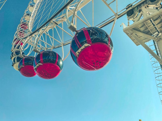 Roda-gigante no centro da cidade contra o céu azul cabines vermelhas aumentam em uma fila de turistas rolando