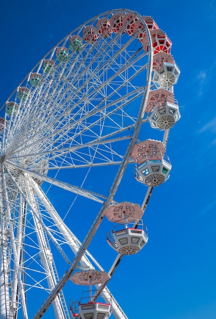 Roda-gigante no fundo do céu azul. No Parque de diversões. O fim de semana