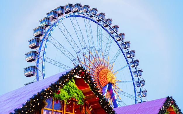 Roda gigante no mercado de Natal à noite na Câmara Municipal de Inverno de Berlim, Alemanha. Rua alemã Natal e feira de férias na cidade ou vila europeia. Decoração do Advento e barracas com itens de artesanato no Bazaar