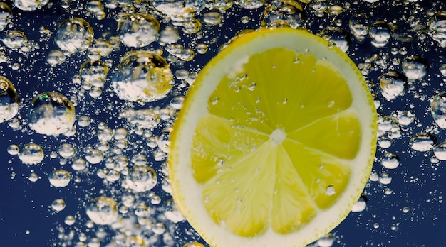 Rodaja de limón bajo el agua en agua de soda o limonada con burbujas Refrescante cóctel gaseoso tónico de soda Primer plano de limones y cubitos de hielo en vaso Cal en salpicaduras de agua con gas bebida fría