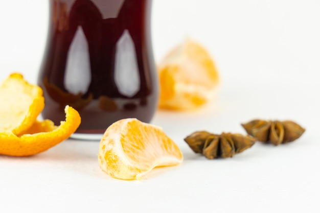 Una rodaja de mandarina frente a un vaso con vino tinto caliente para un aperitivo de Año Nuevo