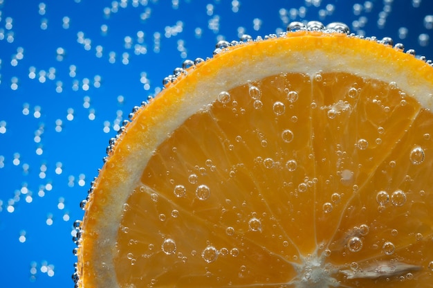 Rodaja de naranja en agua con burbujas de aire