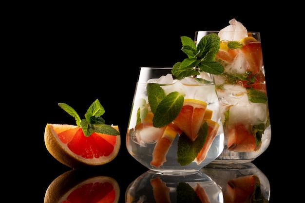 Rodaja de naranja y menta y vaso con bebida de hielo de naranja y menta aislado sobre fondo negro