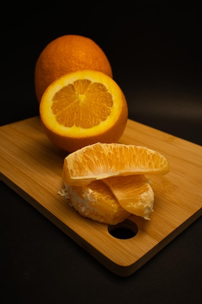 Foto una rodaja de naranja está en una tabla de cortar de madera.