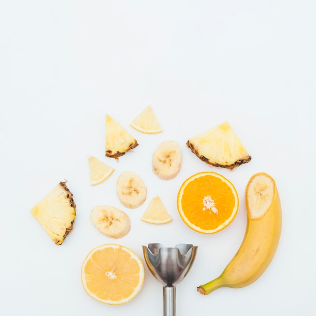 Rodaja De Piña; plátano; Rodajas de naranja con batidora eléctrica de acero inoxidable sobre fondo blanco