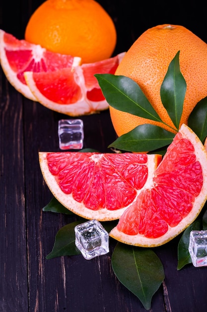 Una rodaja de pomelo con cubitos de hielo sobre un fondo de madera oscura.