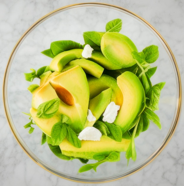 Rodajas de aguacate deliciosa ensalada verde fresca en un recipiente de vidrio sobre la mesa de la cocina de mármol gris comida saludable