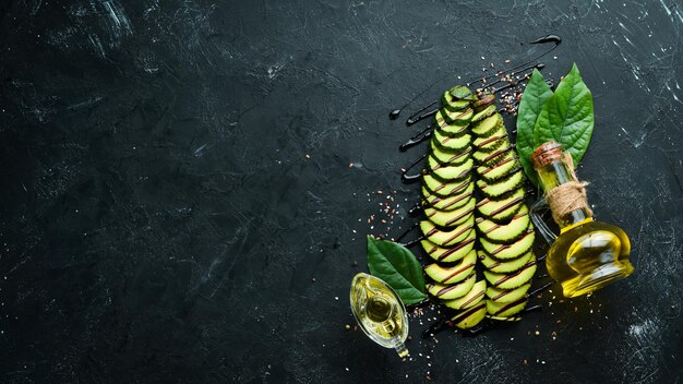 Rodajas de aguacate y especias sobre fondo negro Estilo rústico Vista superior Espacio libre para el texto