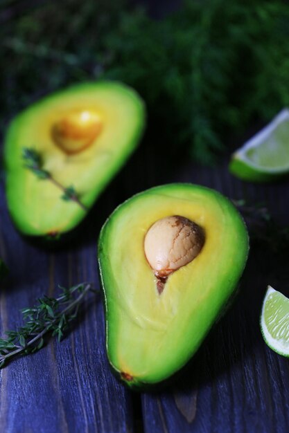 Rodajas de aguacate con lima y hierbas en el primer plano de la mesa de madera