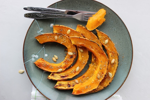 Rodajas de calabaza al horno, espolvoreadas con hierbas secas, rociadas con aceite de oliva.